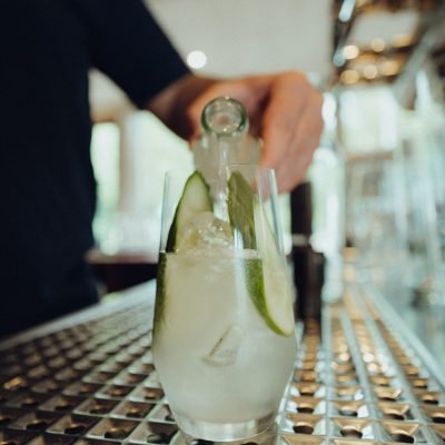 Eine Person gießt ein Getränk ins Glas und kreiert ein erfrischendes Getränk. Lille Helles, Flensburger Pils, Alkoholfreie Getränke Gasthaus Westensee.