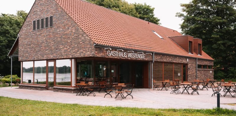 Ein gemütliches Café mit Holztischen und -stühlen, ideal für Kaffee oder Treffen mit Freunden. Beste Restaurants am Westensee, Heißgetränke im Gasthaus Westensee.